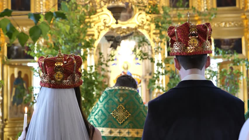Bride and groom wearing crowns during traditional Orthodox wedding ceremony