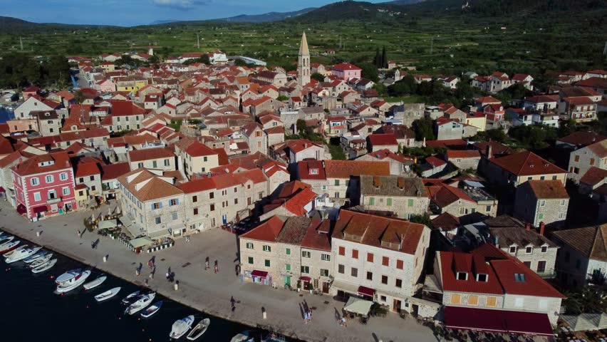 Aerial view of the historic town of Stari Grad with its characteristic red-tiled roofs, stone architecture, and harbor filled with boats in Stari Grad, Split-Dalmatia County, Croatia.