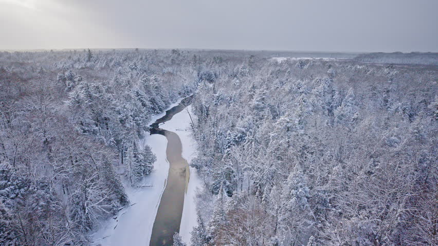 Quiet winter panorama of a snow-covered forest and river winding across Northern Michigan.