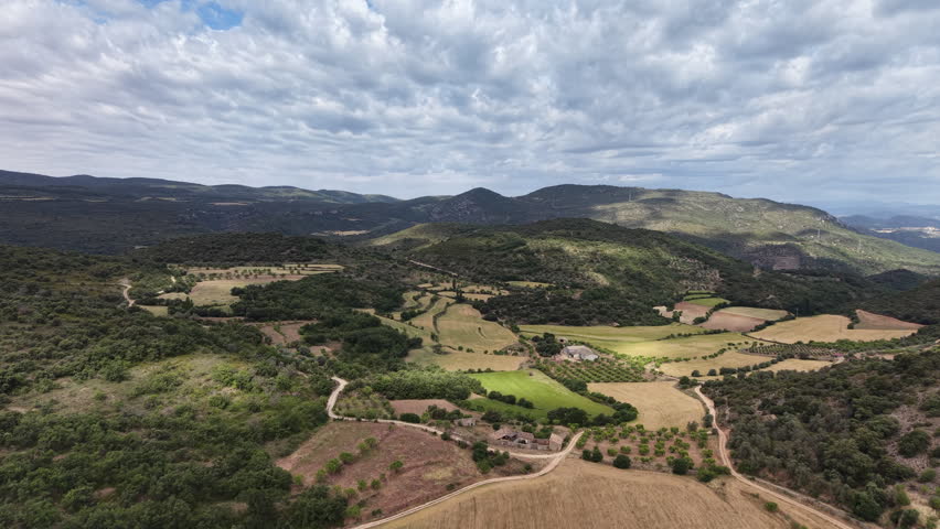 Flying over mountainous Pyrenees landscape with farmland, pastures, olive and almond groves. 