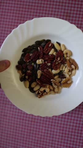 Vertical screen Mixed nuts and seeds served on a plate as a wholesome snack packed with natural ingredients perfect for healthy eating energy and daily nutrition