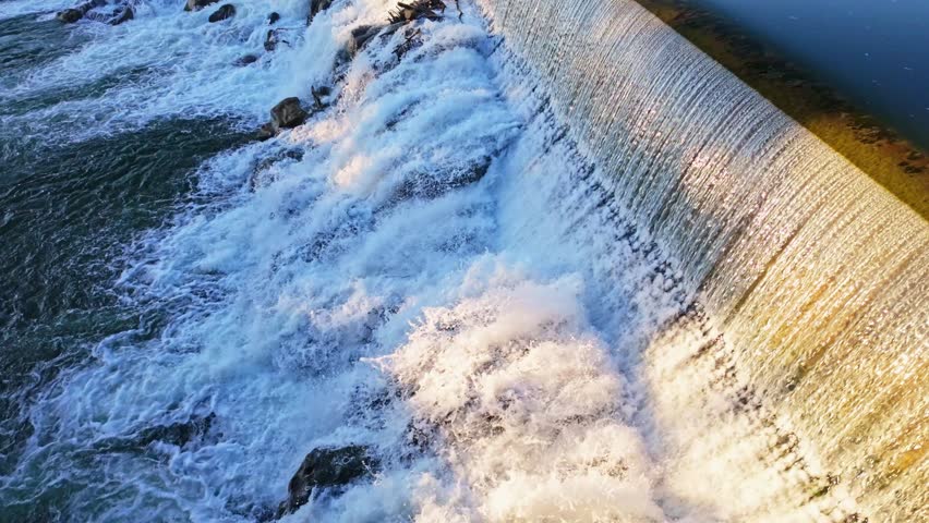 Scenic Snake River waterfall cascading over rocky ledges in warm golden sunset light at Idaho Falls