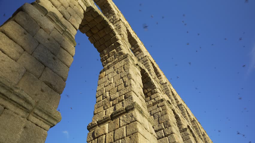 Low angle architectural view of the Roman Aqueduct of Segovia against a clear blue sky