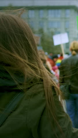 Young adult female feminist demonstration. Gender rights feminism fight. Women march movement power sign equality. Gender woman strike empowerment action. Social message. Crowd people city street day.