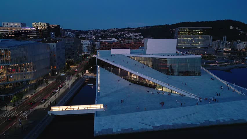 Aerial view of the modern Oslo Opera House with its iconic sloping roof and glass facade illuminated at twilight in Oslo, Oslo, Norway.