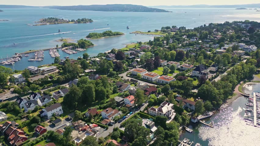 Aerial view of Bygdoy peninsula featuring lush greenery, residential houses, and a marina with boats along the coastline in Oslo, Oslo, Norway.