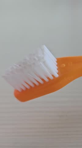 A person prepares to brush their teeth. They place toothpaste on a toothbrush. The activity takes place in a bathroom. The focus is on dental care.