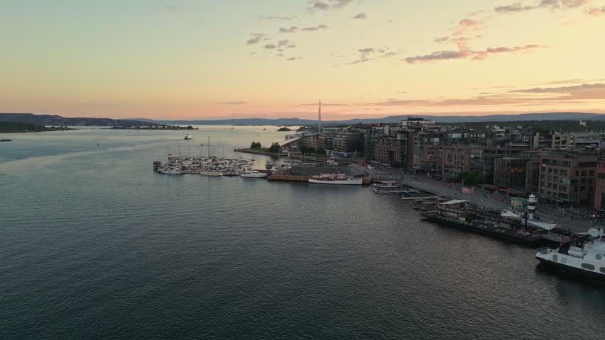 Aerial view of the Oslo waterfront at sunset with boats docked at the pier and modern buildings along the harbor in Oslo, Oslo, Norway.