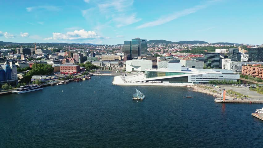 Aerial view of the modern Oslo Opera House situated on the waterfront with boats in the harbor and the cityscape of Oslo, Oslo, Norway.