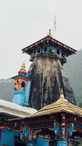 Beautiful view of Omkareshwar Temple in Ukhimath, Uttarakhand, featuring colorful pillars and traditional Himalayan architecture surrounded by mist-covered mountains.