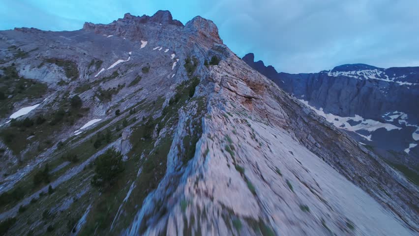 Breathtaking FPV drone ascent soaring up the narrow limestone ridge of Mount Olympus into thick drifting clouds. The dynamic first-person flight skims low over rugged mountain trails, capturing high-altitude alpine majesty