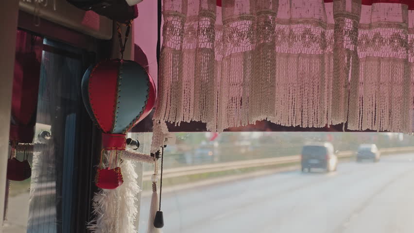 Decorative hot air balloon hanging on a bus window during a road trip with traffic on the highway