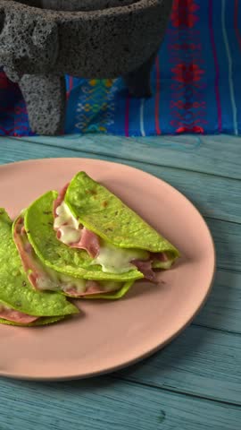 Ham and melted cheese quesadillas served on green cactus tortillas on a pink plate