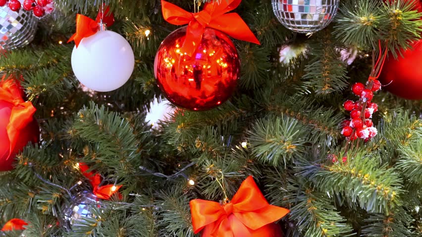 Many ornaments and decorations on a beautiful decorated Christmas tree. Red baubles and lights.