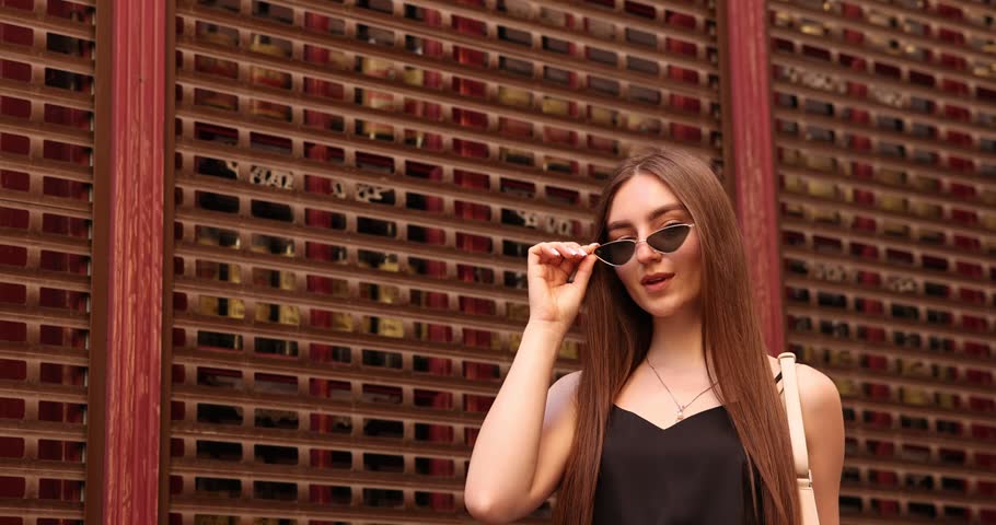 Beautiful young woman in stylish sunglasses outdoors, low angle view