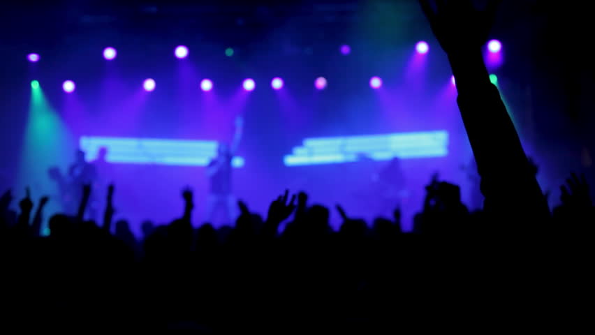 Rock band performs at night for a gathered crowd, with musicians on stage and audience energy building the atmosphere of a live concert event.