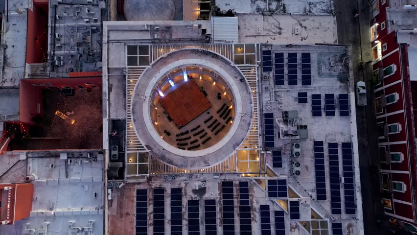 Aerial top down view of people rehearsing in the circular concert hall of the Yucatan Palace of Music, a modern cultural center surrounded by colonial buildings in the historic center of Merida
