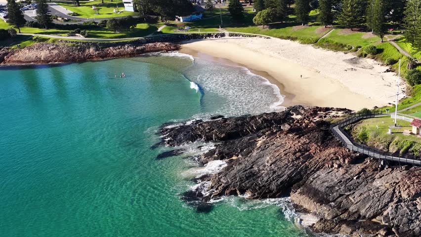 High angle drone shot of turquoise waves crashing on Horseshoe Bay in South West Rocks.