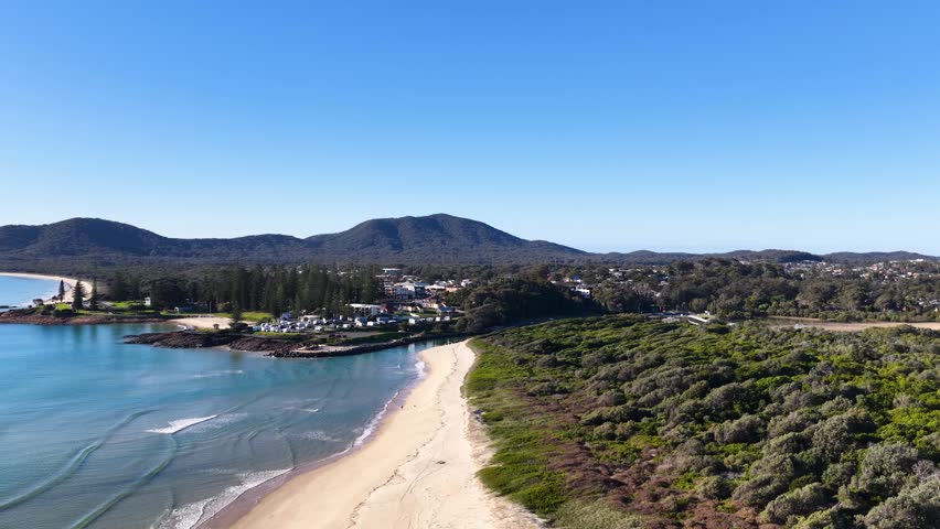 High-angle aerial drone shot of sandy beaches and coastal mountains in South West Rocks, Australia.