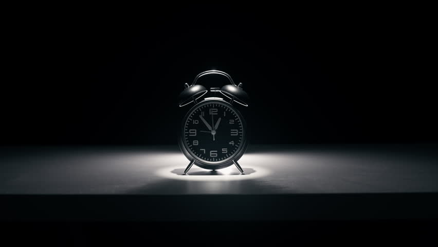 Black alarm clock on a black background.