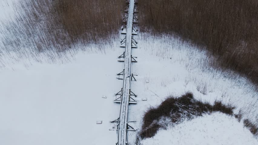 Drone follow wooden boardwalk stretching across Lake Kanieris wetland from above