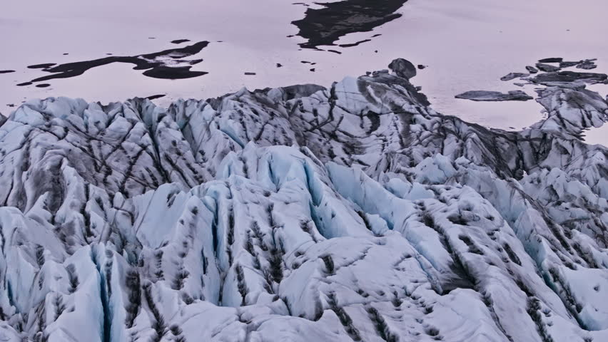 Top drone view of cracked rugged Hoffellsjökull glacier ice field in Iceland. Detailed visual of textured glacier cracks and geological sediment deposits