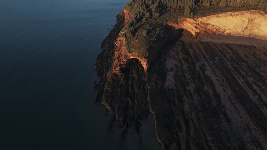 A top-down view of a dramatic sea cave opening carved into cliff edges along the Bay of Fundy in New Brunswick, Canada