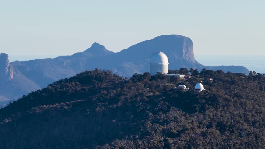Wide shot of astronomical telescope domes on a mountain ridge in Warrumbungle National Park.