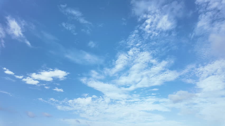 Time lapse of fluffy white clouds moving fast across bright blue sky on a sunny day