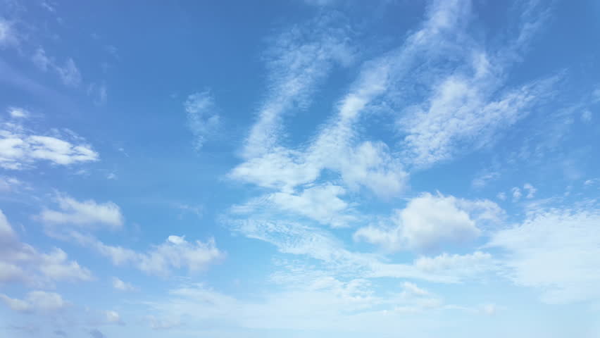 Time lapse of fluffy white clouds moving fast across bright blue sky on a sunny day