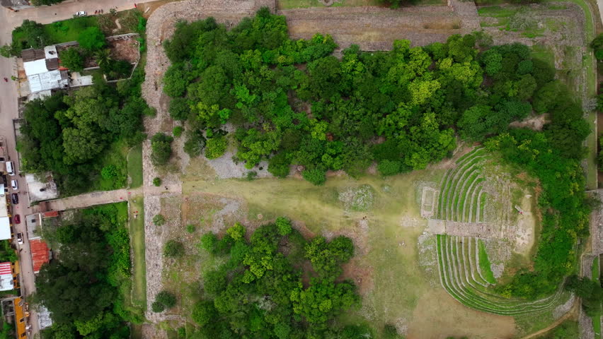 Aerial drone view of leafy village lots on the edge of Izamal, Yucatan, Mexico, low houses nestled among dense green trees and tropical vegetation.