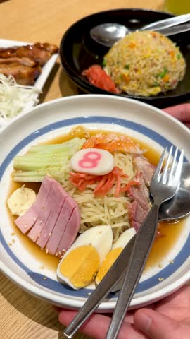 Close-up of chilled ramen noodles with colorful toppings served in a restaurant in Bangkok.