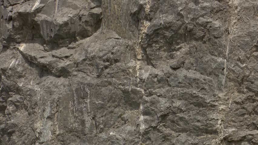 Close up detailed texture of dark gray jagged rock wall the rugged surface