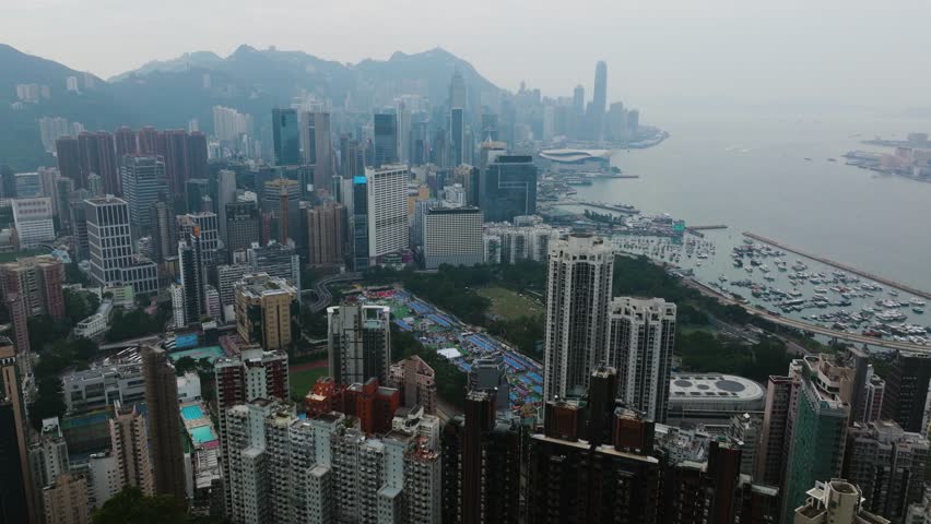 Misty day drone shot flying over dense Hong Kong high rise buildings, cloudy day