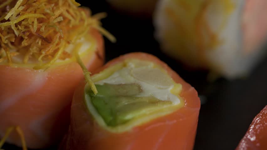 Chef adding crispy sweet potato topping on salmon sushi close up