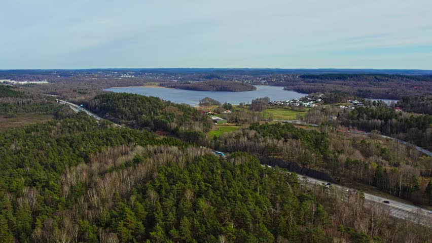 Aerial drone view showing Helenevik residential area beside Radasjon lake surrounded by forest near Gothenburg Sweden. Scenic landscape highlighting peaceful countryside during daytime