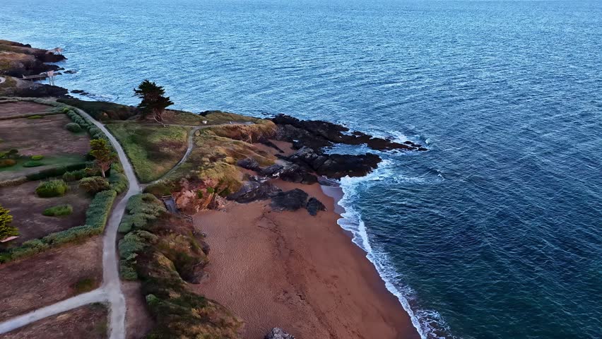 Aerial view of the rugged coastline with sandy beach, rocky outcrops, and coastal path in Nantes, Pays de la Loire, France.