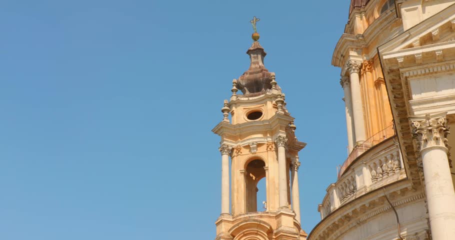 Close view of the Basilica of Superga bell tower and facade in Turin, Italy, framed against a clear blue summer sky.