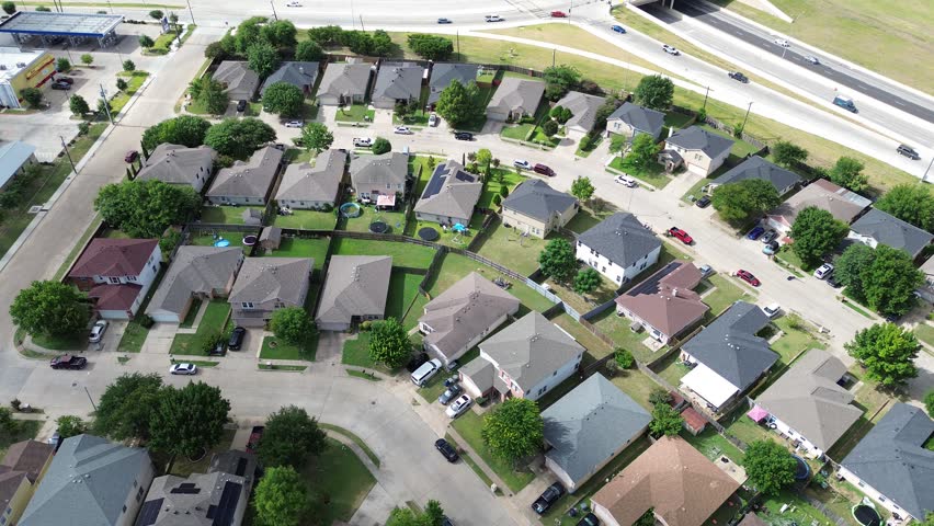 Winding subdivision streets border commercial lots elevated highway overpasses, showcasing high density housing single family configurations within Pleasant Grove, Dallas Fort Worth suburbs, Texas. US