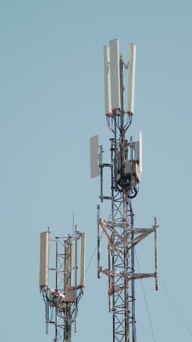 Close up of a telecommunications antenna mounted on a metal tower structure against a clear blue sky