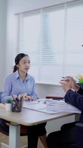 Two business women are sitting and talking in the office and discussing projects on laptops and graphs working together in the office.