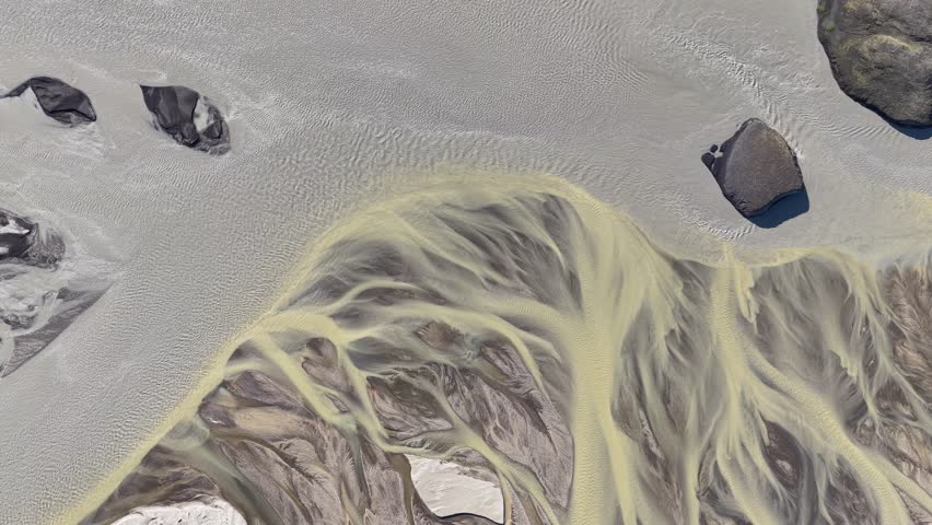 Aerial view of a braided glacial river system with sediment-rich water flowing through the landscape of Iceland.