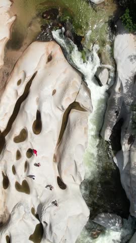 Aerial view of a group of people relaxing on unusual white rock formations next to a river