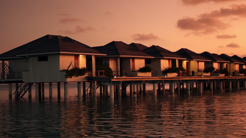 Calm Tropical Ocean Beside Luxury Overwater Bungalows at a Maldives Island Resort During Golden Sunset