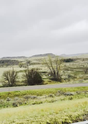 A Montana country highway with rolling terrain in cool mountain spring temperatures and clear to cloudy skies, captured views by a big rig truck passenger point of view facing forward and side to side 