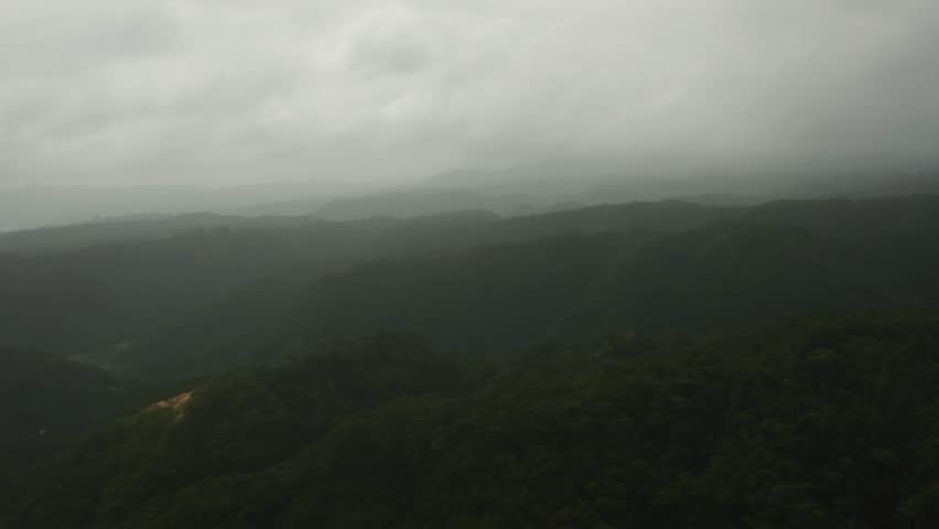 A wide-angle shot of misty forested mountains fading into layers, creating a soft atmospheric landscape in Okinawa, Japan