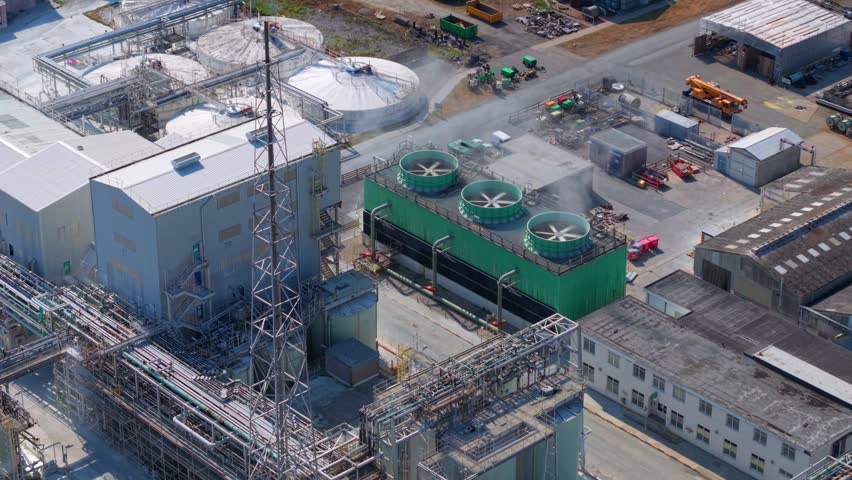 Aerial view of industrial chemical manufacturing facility with cooling towers, storage tanks, and complex pipe networks at an industrial site in Stallingborough, England, United Kingdom.