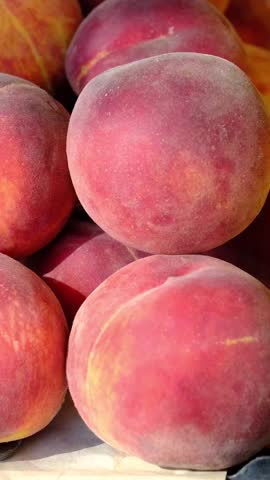 Fresh ripe peaches with nectarines and lemons displayed at local farmers market on sunny summer day, colorful seasonal fruit selection, healthy organic produce ready for sale