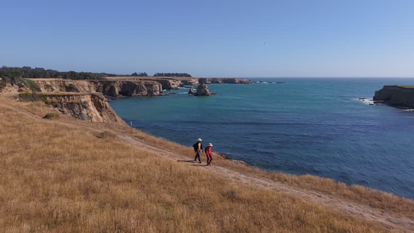 Man and woman walk together on the Point Arena trail near the lighthouse along the northern California coast.