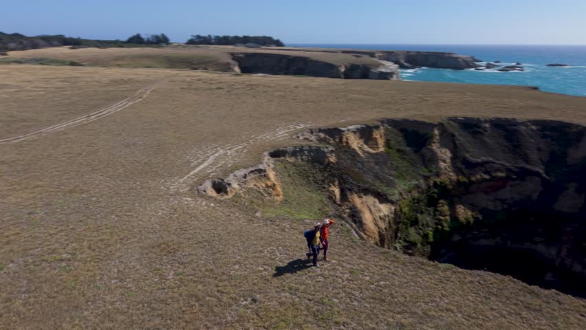 A man and a woman hike together along the cliffs on the Point Arena trail near the lighthouse south of Mendocino.